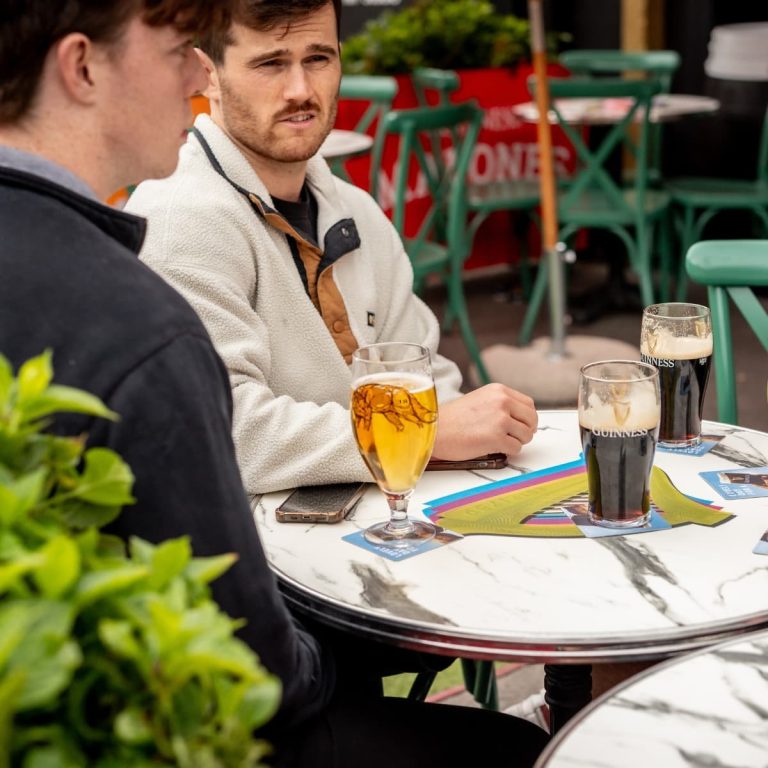 Two guys catching up over pints in the outdoor beer garden at Malones Leith