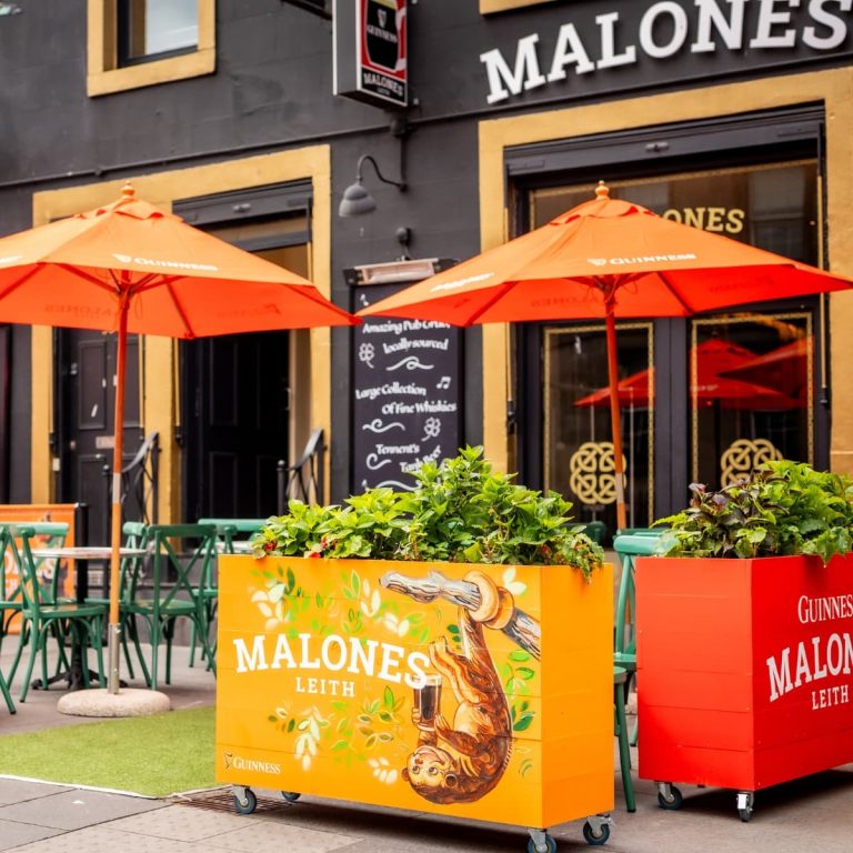 The beer garden at Malones Leith including the umbrellas, planters, and artificial grass